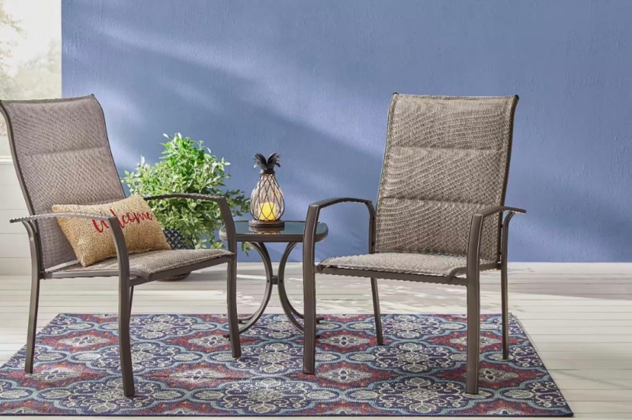 two brown sling chairs with glass table on rug 