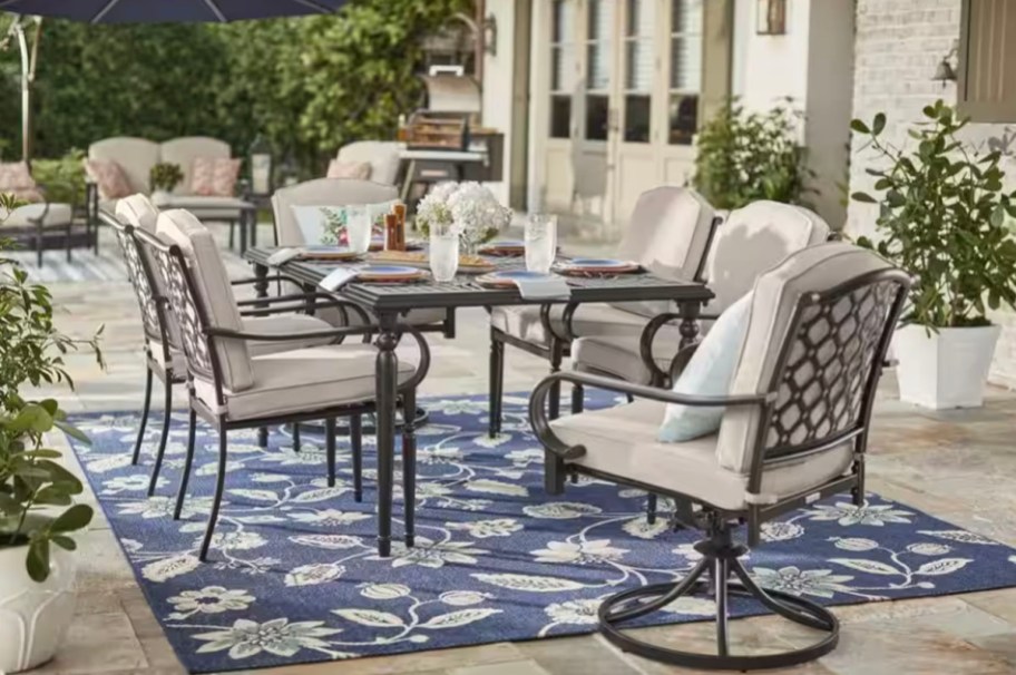 beige and brown patio chairs and tabnle on blue rug 
