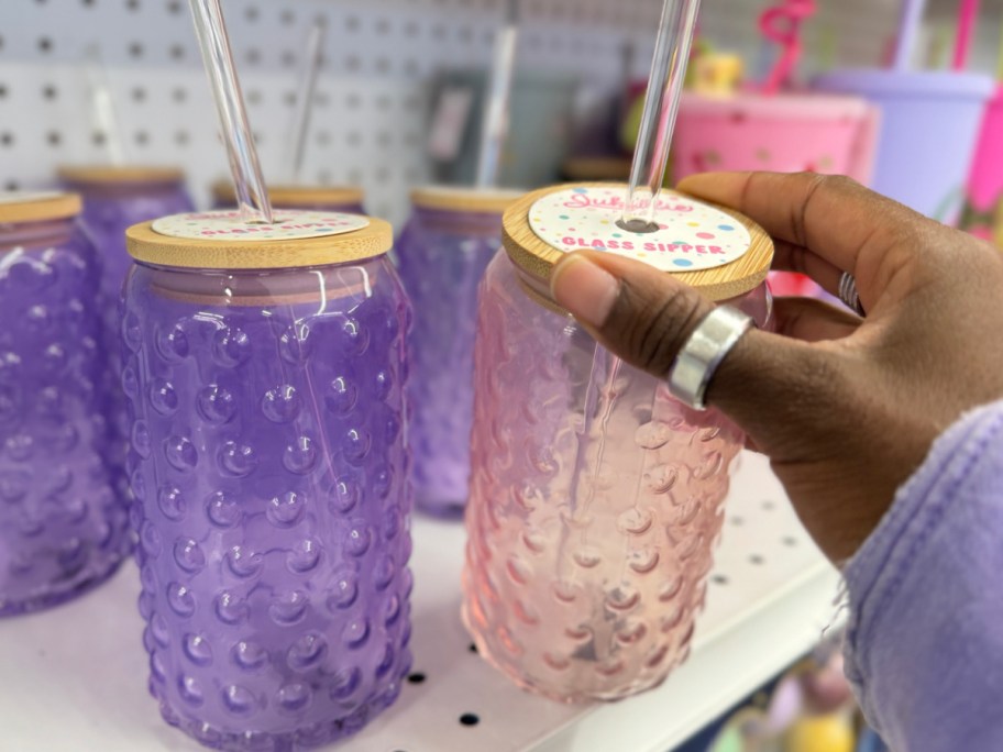 hand holding five below glass sipper cups in purple and pink