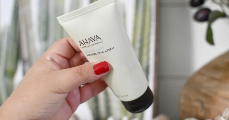 holding a bottle of ahava hand lotion