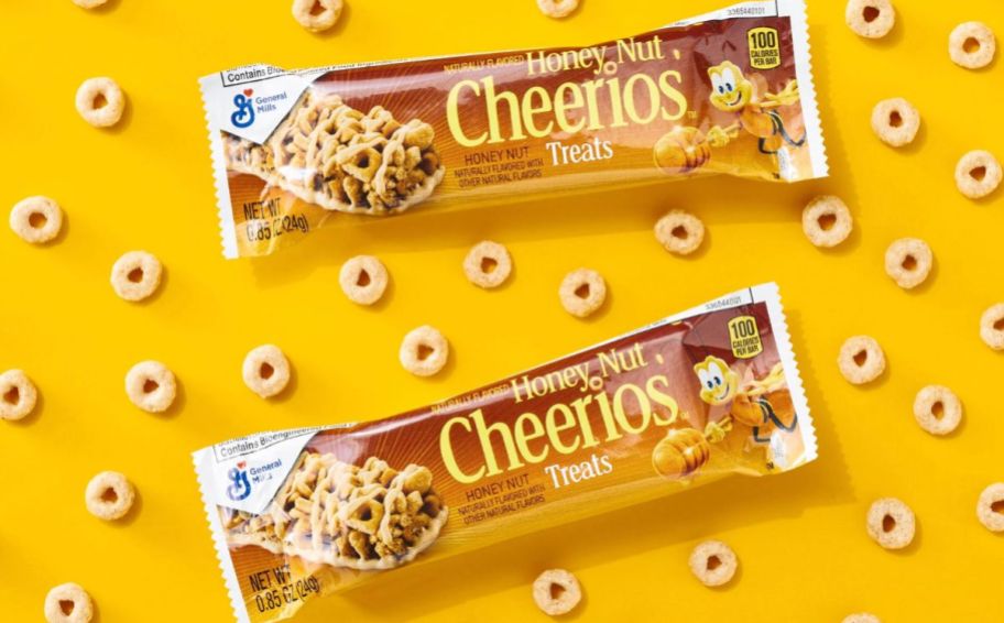 two honey nut cheerios cereal bars on a yellow background with cheerios scattered around 