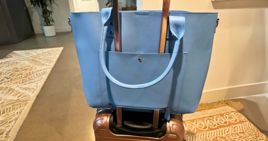 blue travel bag over the handle of a suitcase