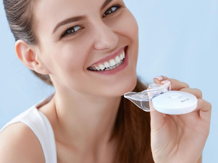 woman smiling holding LED teeth whitening mouthpiece