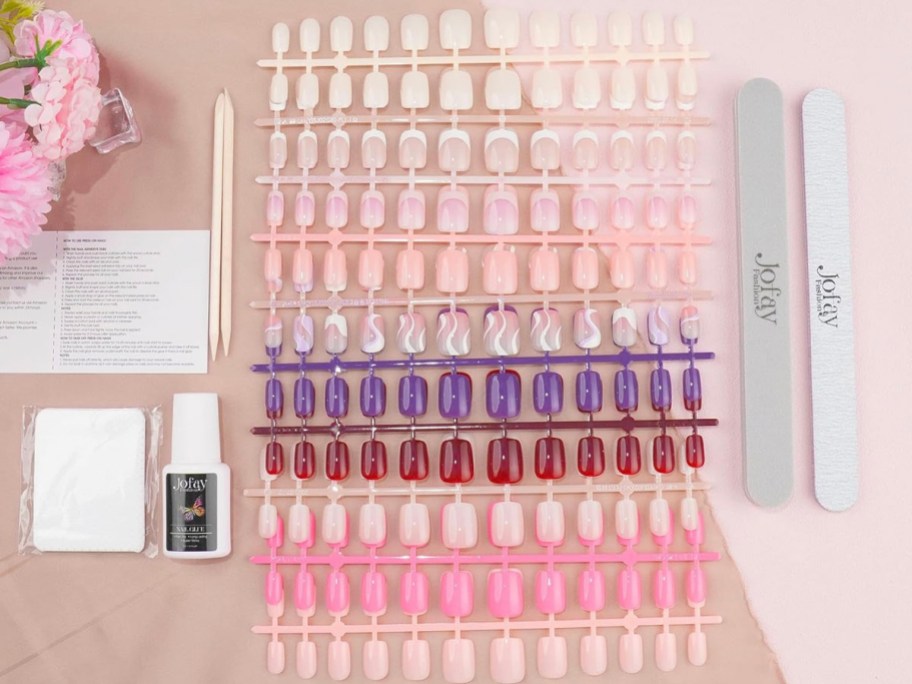 fake nails lined up with glue, and cuticle sets on table