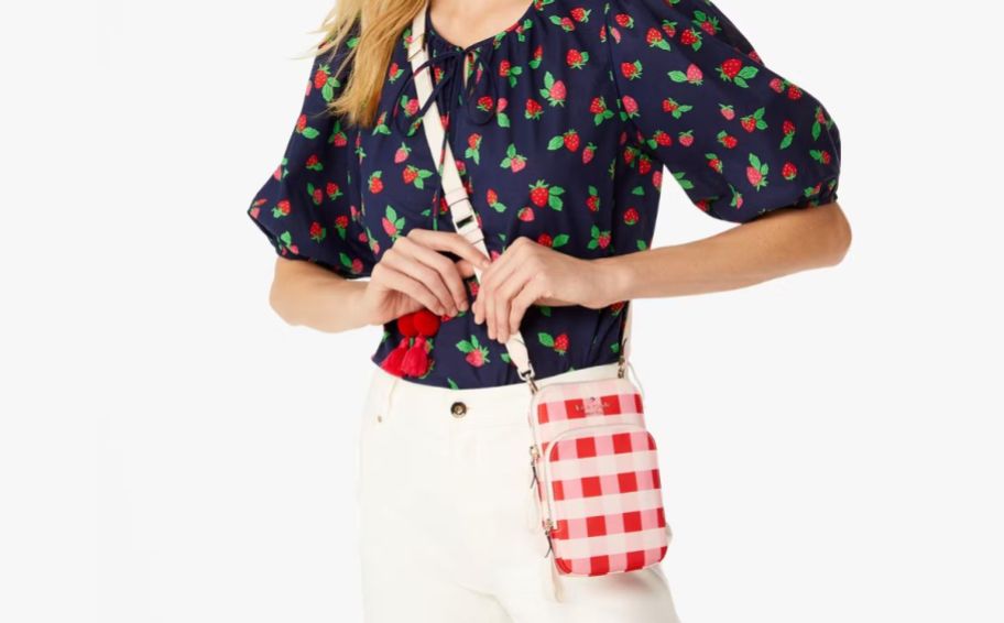 a model wearing a red gingham check Kate spade phone crossbody
