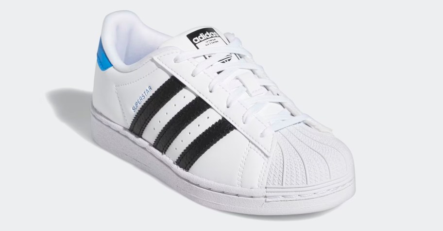 kids white sneaker with black stripes and blue marking on heel