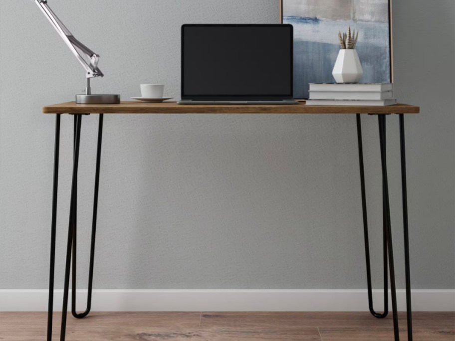 wood and black desk with laptop and lamp on top