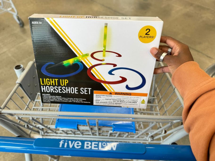 a womans hand placing an led horse shoe set into a shopping cart