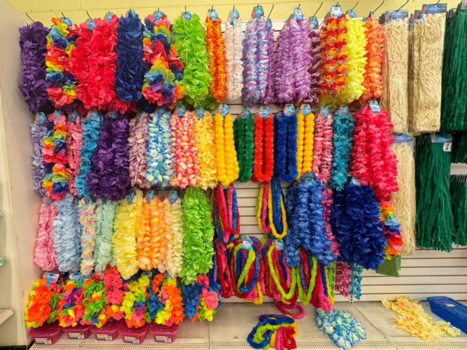 Colorful assorted leis hanging on a peg board in a store