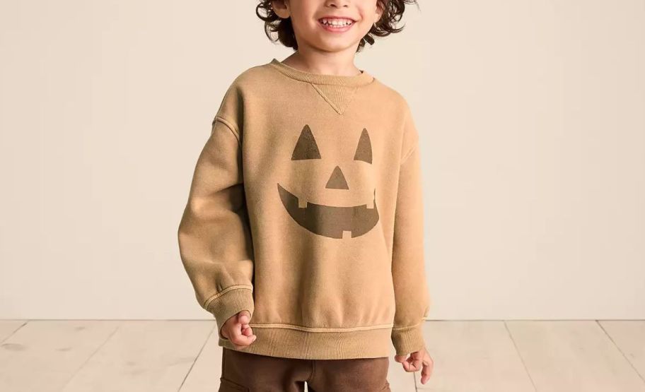 a little boy wearing a jack o' lantern sweatshirt