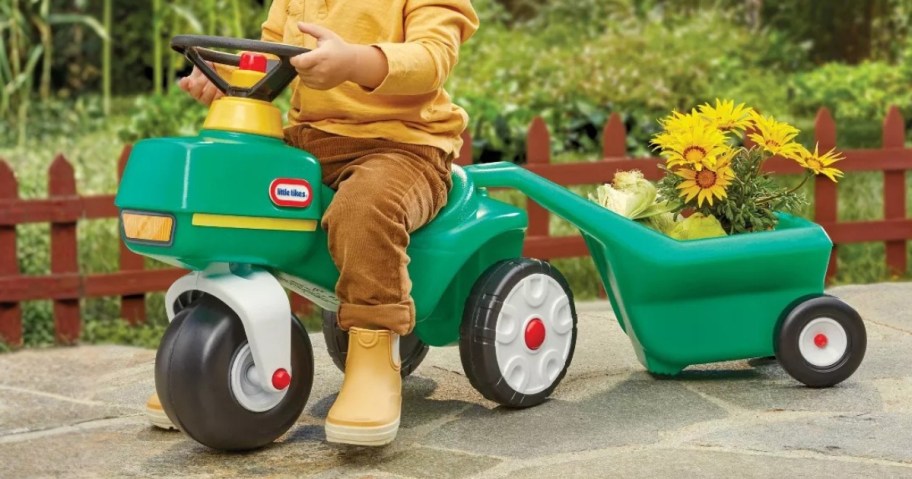a little boy riding on a Little Tikes green tractor