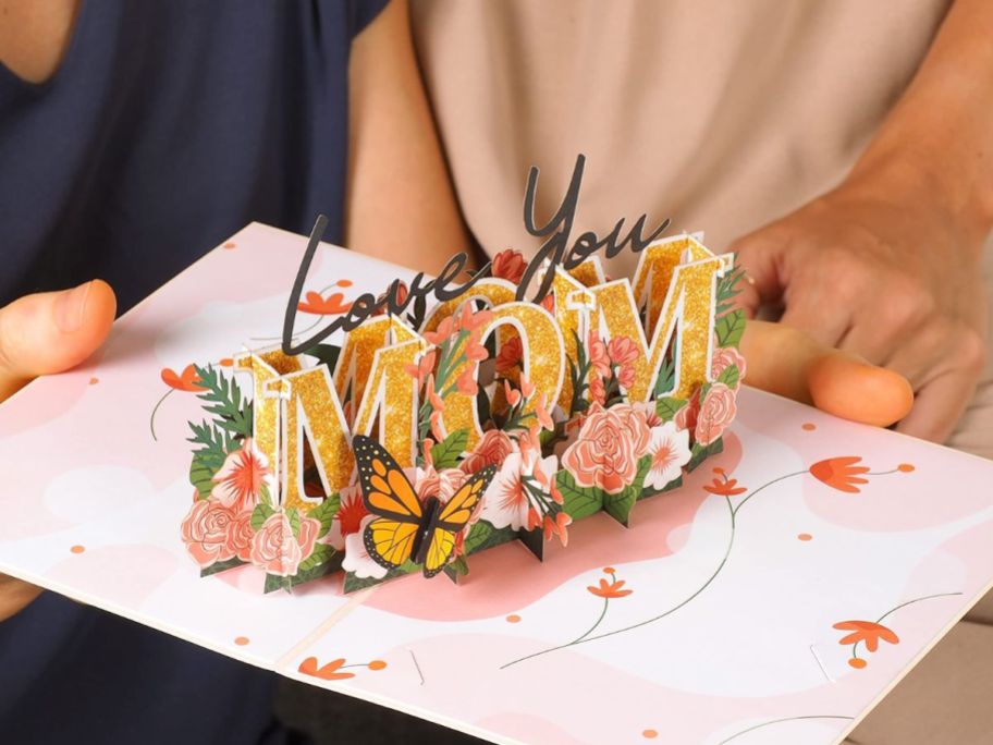 hand holding up a pop up card that reads love you mom