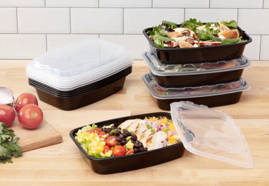 black meal prep containers filled with food with clear lids on table