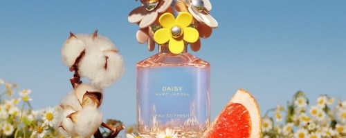 butterfly on top of marc jacobs daisy perfume surrounded by fruit and flowers