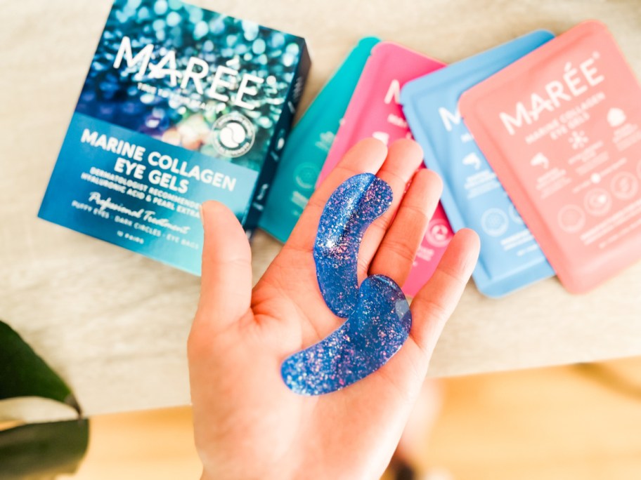 hand holding two blue sparkly eye gel patches above box