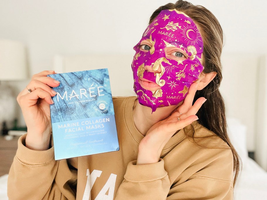 woman wearing pink celestial facial mask and box