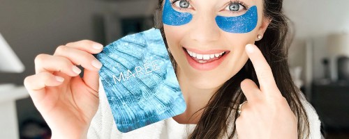 woman wearing blue eye gels holding pack in front of her