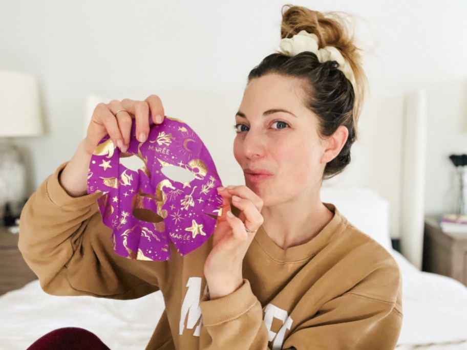 woman holding up purple sheet face mask