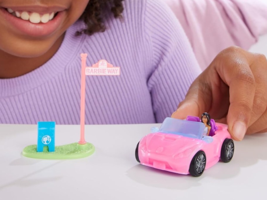 little girl playing with a mini BarbieLand toy convertible set