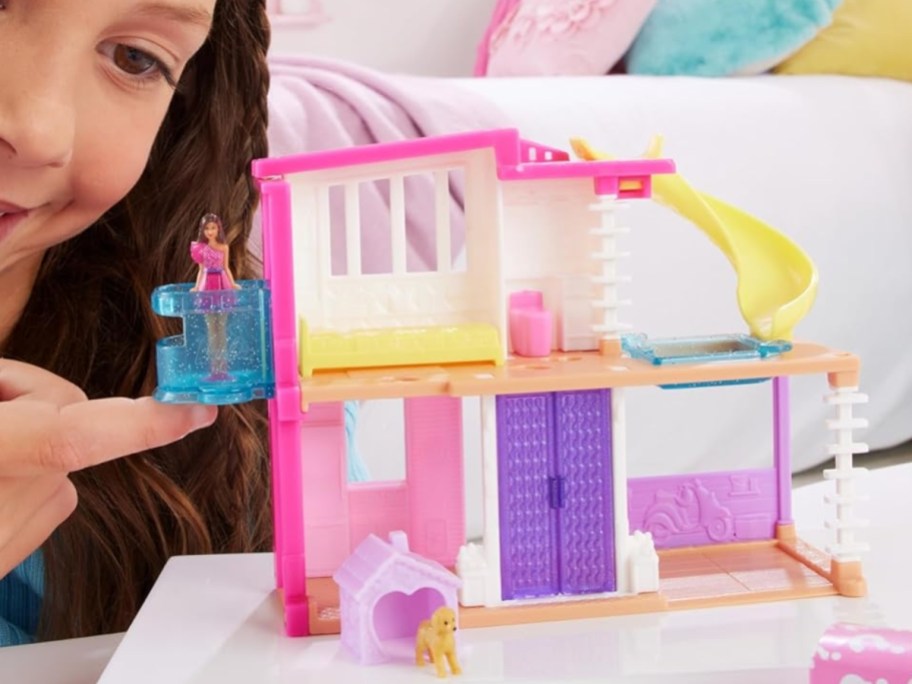 little girl playing with a mini BarbieLand toy dreamhouse set