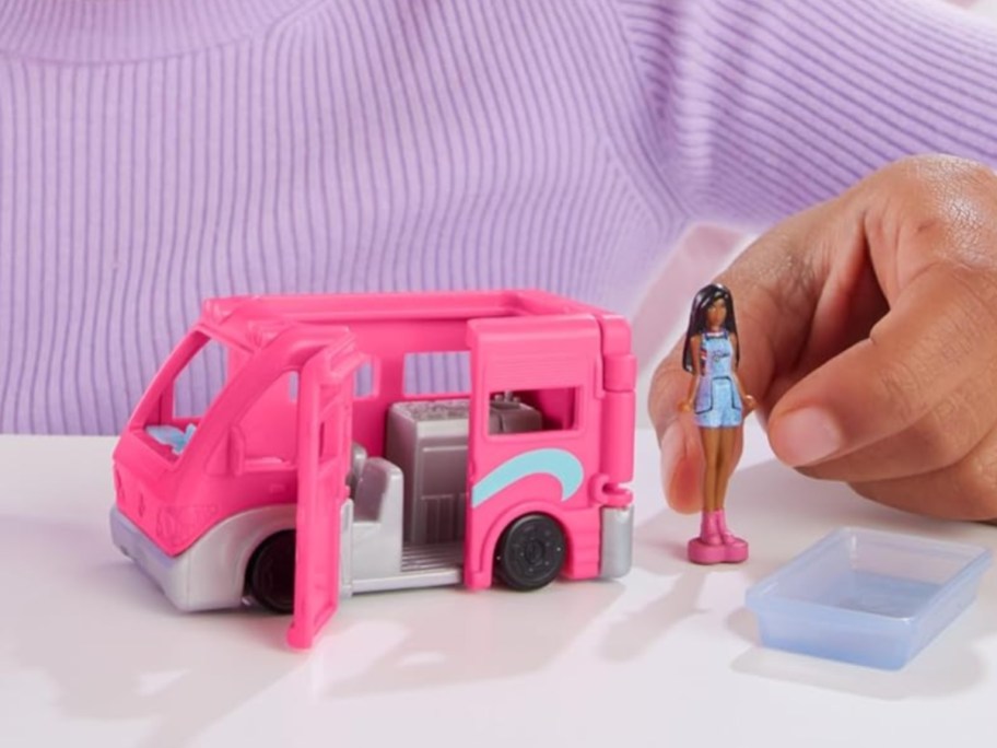 little girl playing with a mini BarbieLand toy DreamCamper set