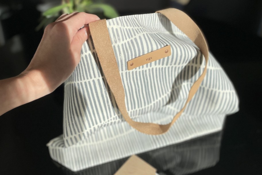 hand holding wavy striped tote bag in sunlight