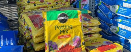 miracle gro potting mix bag sitting in front of stack of bags