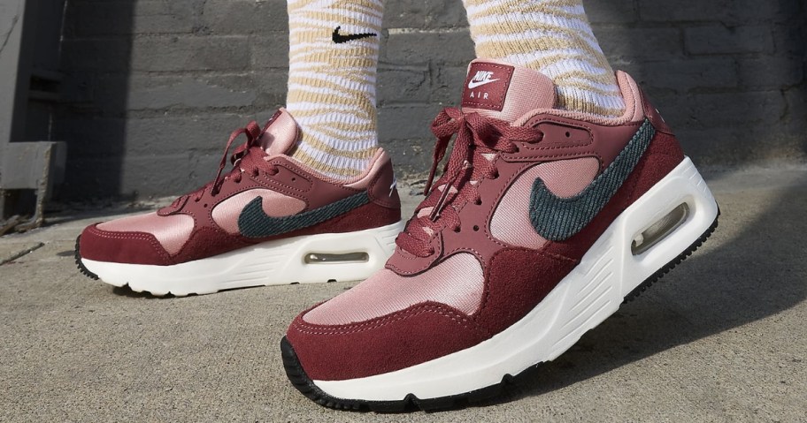 women's feet wearing pink Nike Air Max shoes and brown and white Nike socks
