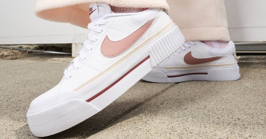 women's feet wearing white, pink and yellow Nike platform court shoes