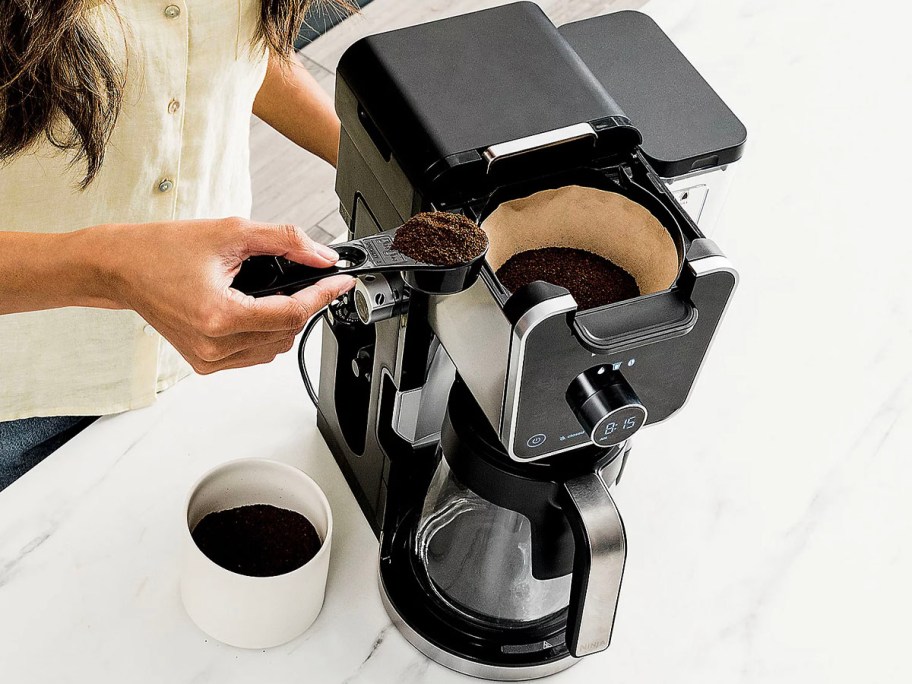 hand putting coffee in ninja coffee maker