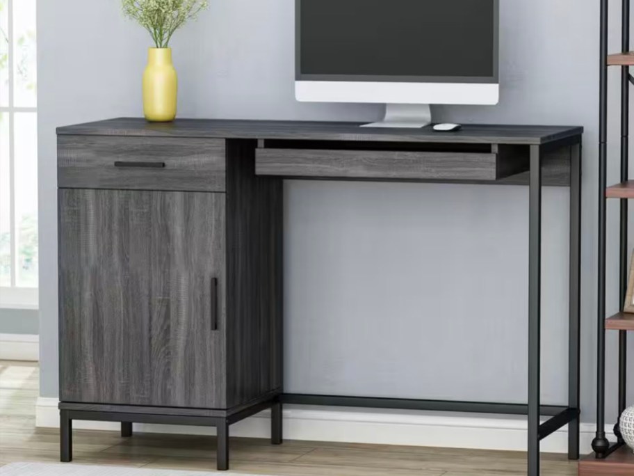 gray desk with computer and vase on top