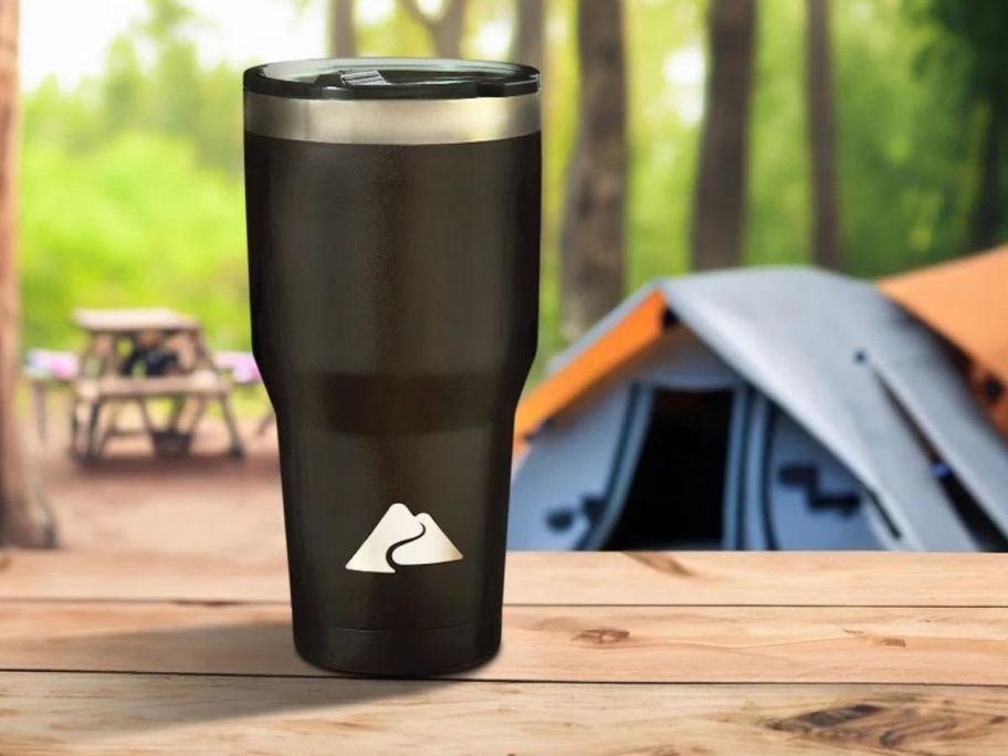 Ozark Trail 32 oz Vacuum Insulated Stainless Steel Tumbler, Black on picnic table at campsite