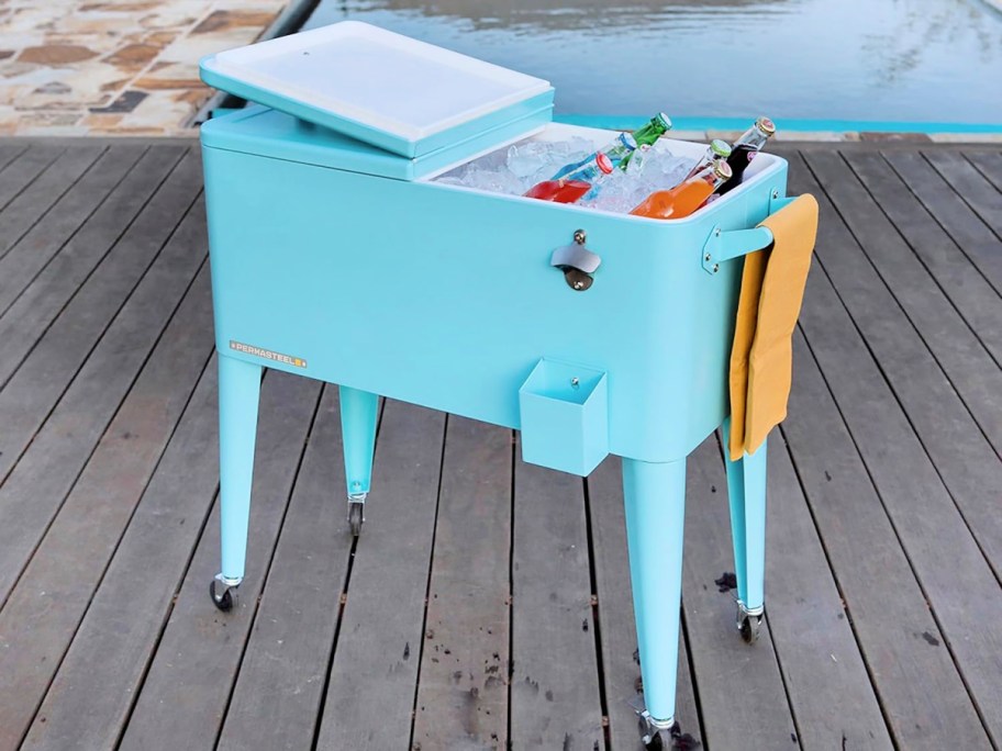 Permasteel 80 Qt. Turquoise Chest Cooler full of ice and bottled beverages with an orange towel hanging from the side