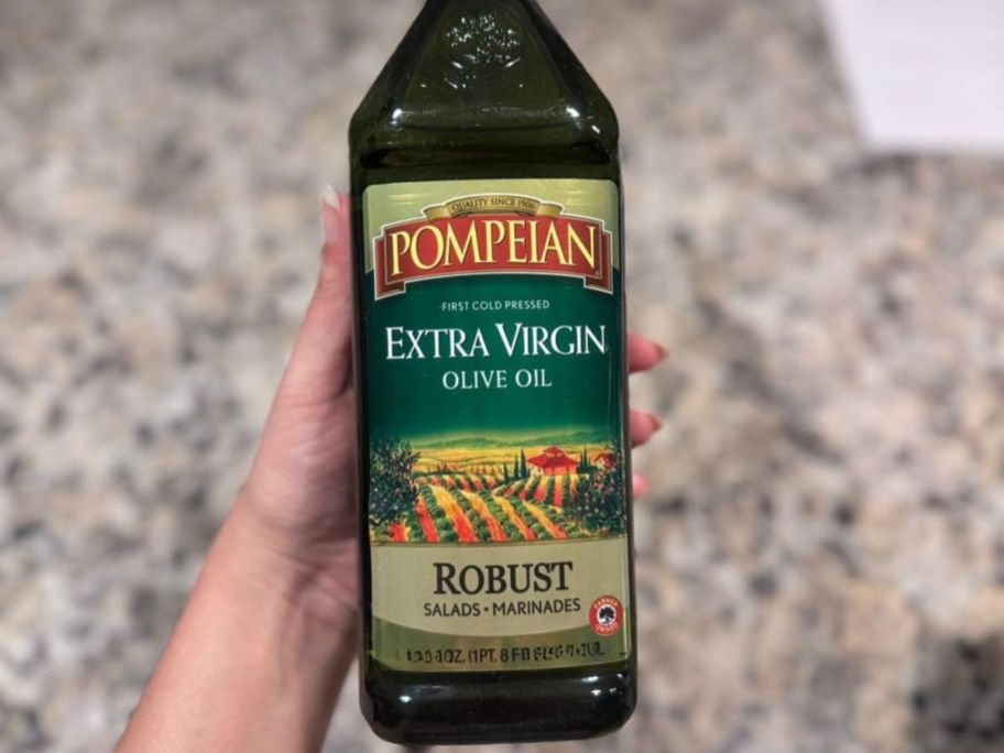 hand holding pompeian olive oil bottle in kitchen