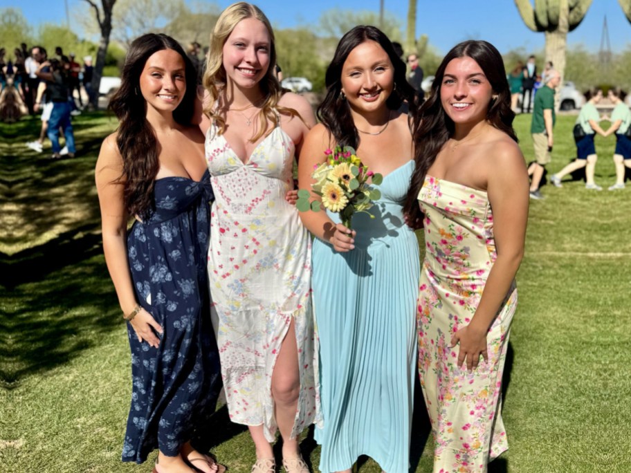 four girls in prom dresses standing outside