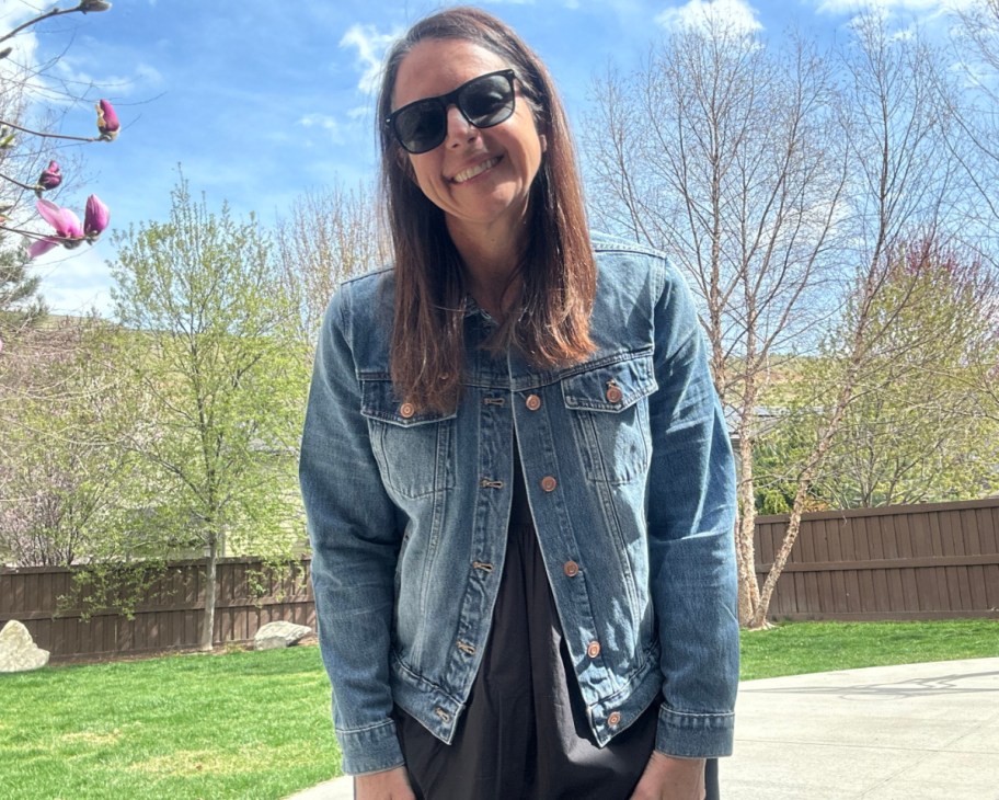 woman wearing denim jacket and black dress outside