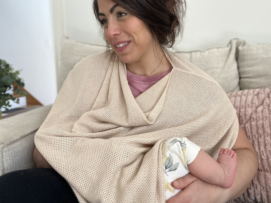 woman nursing baby under mesh shawl