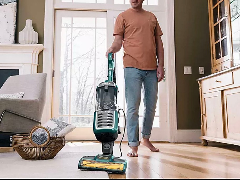 man using vacuum in living room on hardwood floor