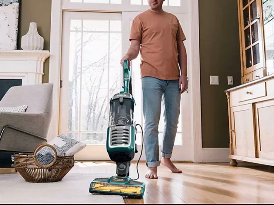 man using vacuum in living room on hardwood floor