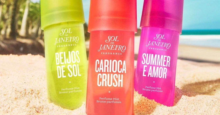 three sol de janiero perfume mists sitting in sand with beach in background