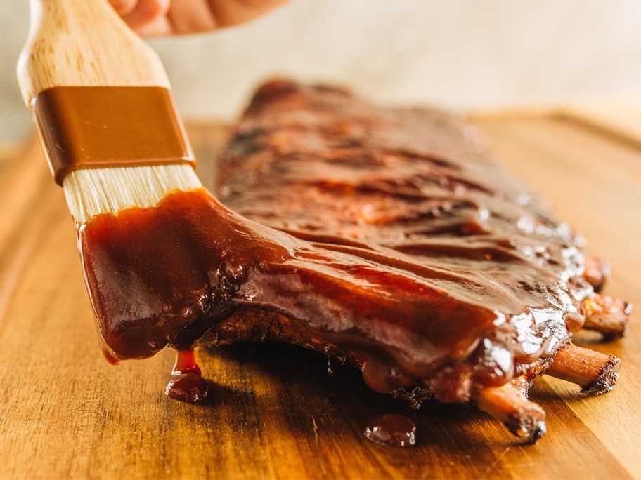 using a brush to add barbeque sauce to ribs