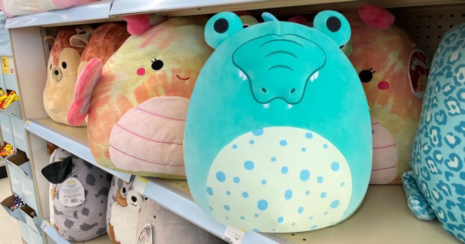 alligator squishmallow on store shelf with other squishmallows on shelf behind it