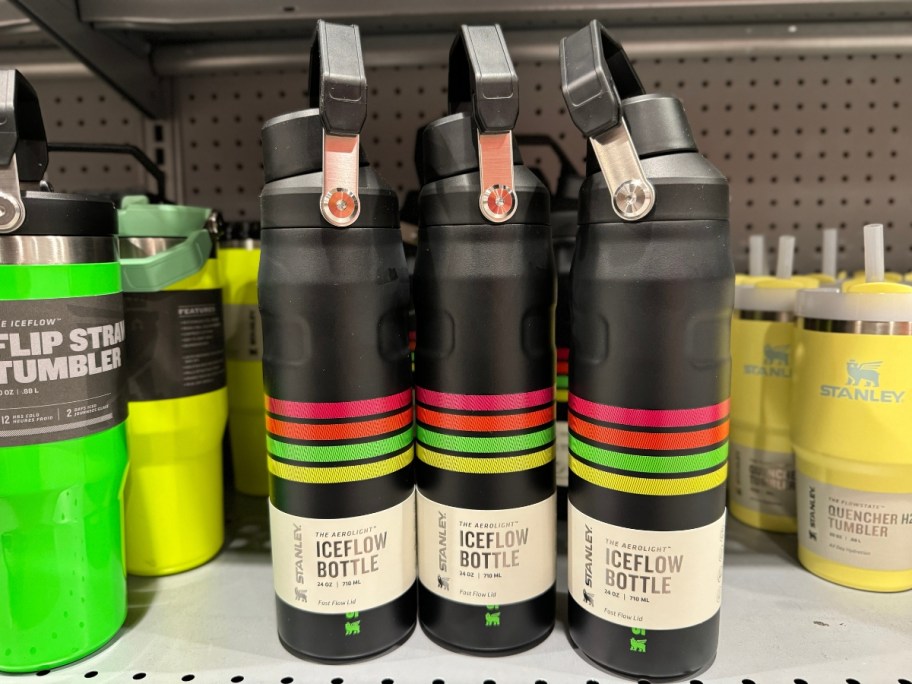 3 black Stanley bottles with neon color strips on shelf