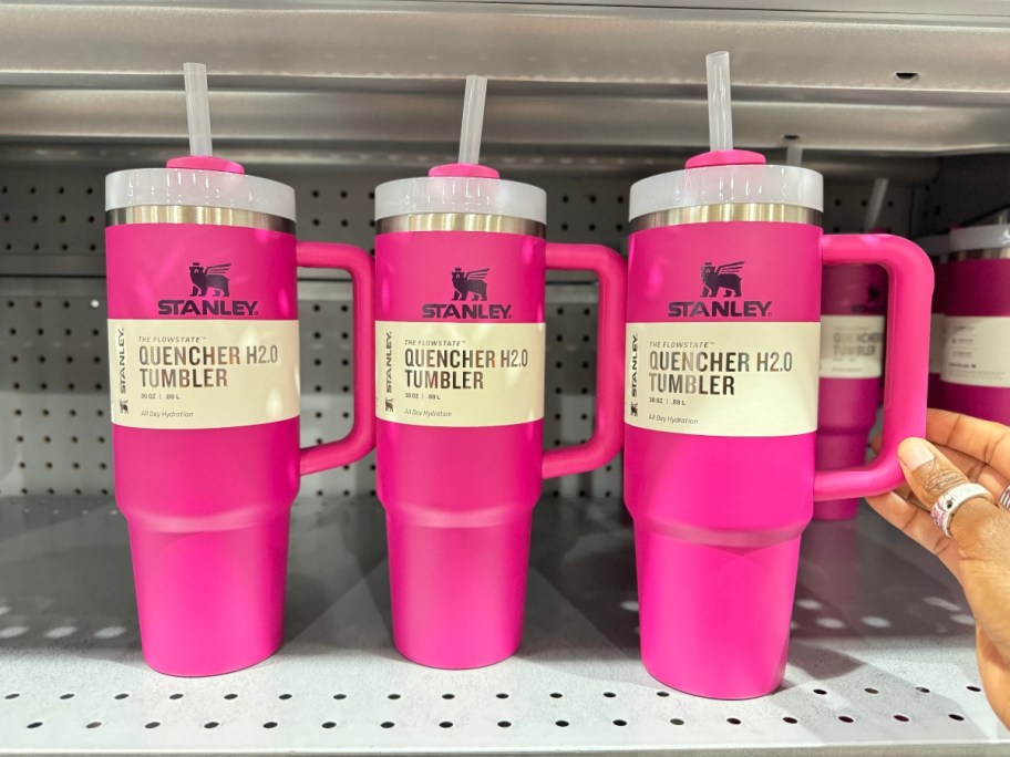 3 stanley tumblers in fuchsia pink on a shelf