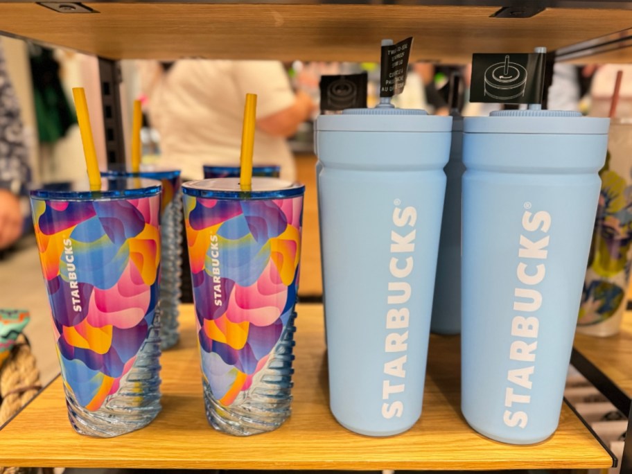 multi-color Starbucks tumbler and light blue Starbucks cold cup on shelf