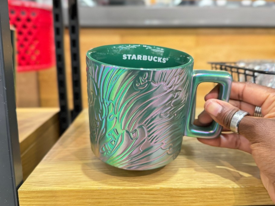 hand picking up a green, purple, pink iridescent Starbucks mug