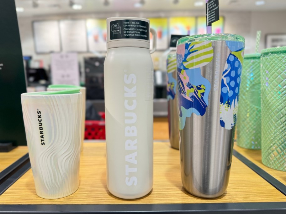 Starbucks tumblers and water bottle on shelf