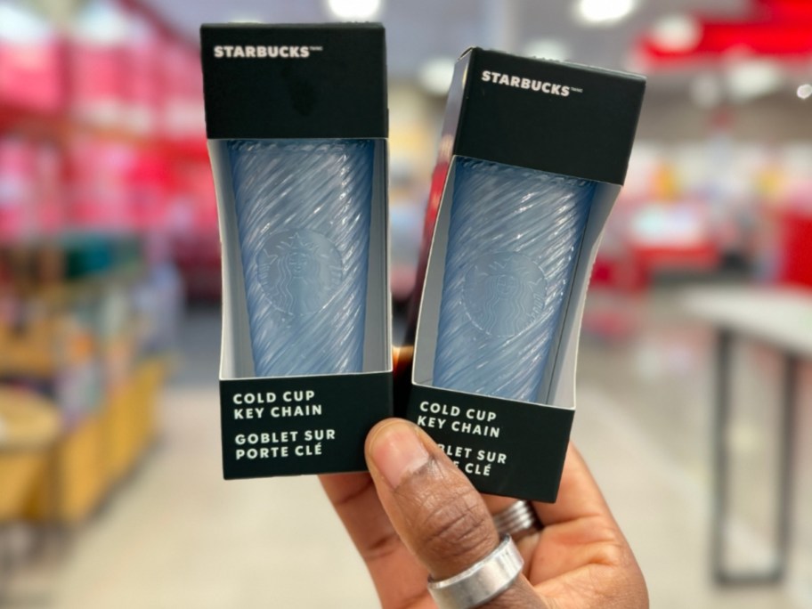 hand holding 2 blue Starbucks Cold Cup Keychains in packaging