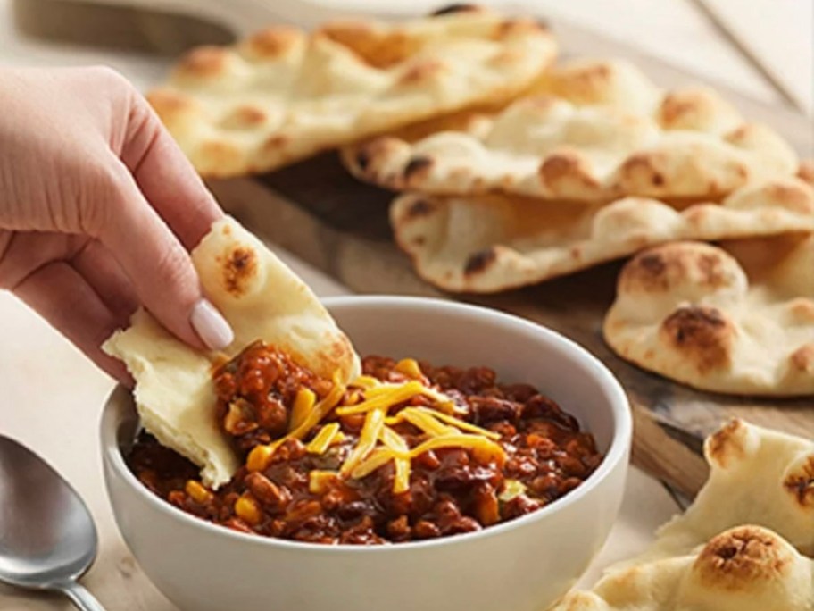 hand getting chili out of naan rounds 