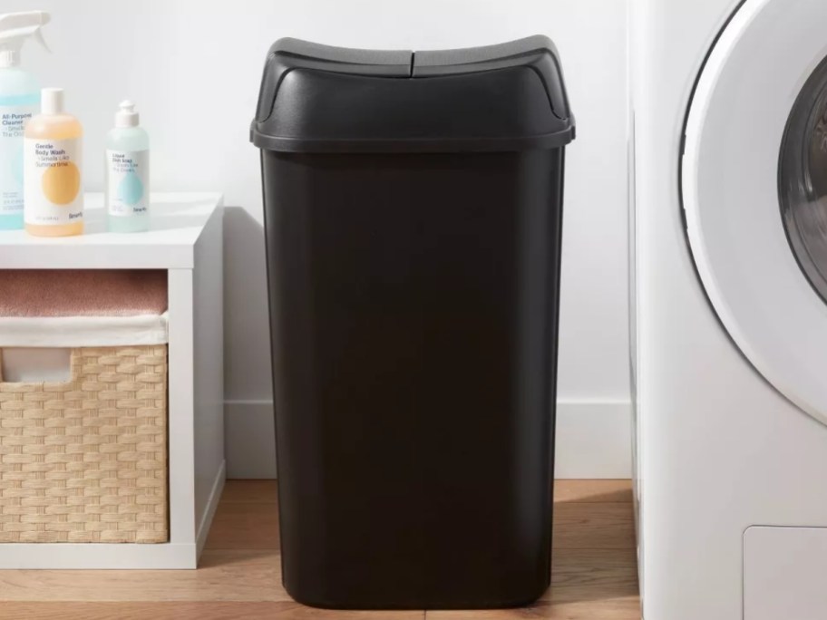 black plastic trash can in a laundry room